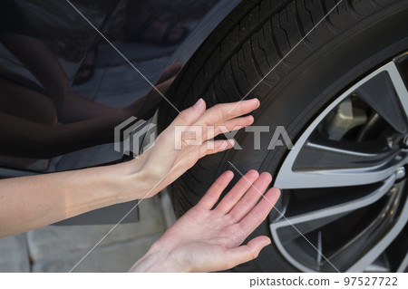 Female driver hands inspecting wheel tire of her new car. Vehicle safety concept Female driver hands inspecting wheel tire of her new car. Vehicle safety concept 97527722