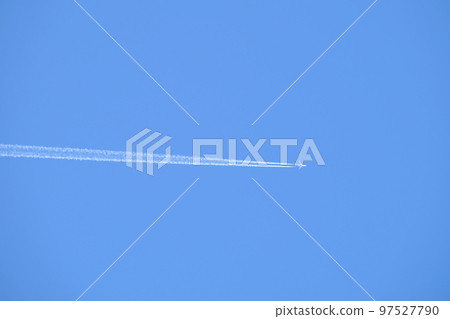 Distant passenger jet plane flying on high altitude on clear blue sky leaving white smoke trace of contrail behind. Air transportation concept. 97527790