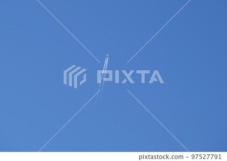 Distant passenger jet plane flying on high altitude on clear blue sky leaving white smoke trace of contrail behind. Air transportation concept. Distant passenger jet plane flying on high altitude on clear blue sky leaving white smoke trace of contrail behind. Air transportation concept. 97527791