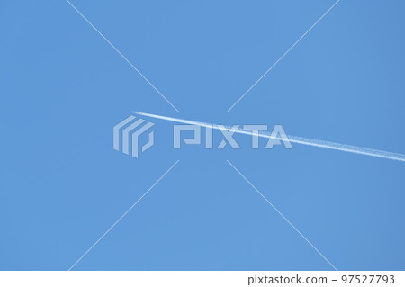 Distant passenger jet plane flying on high altitude on clear blue sky leaving white smoke trace of contrail behind. Air transportation concept 97527793