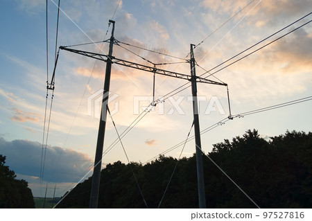 Dark silhouette of high voltage tower with electric power lines at sunrise. 97527816