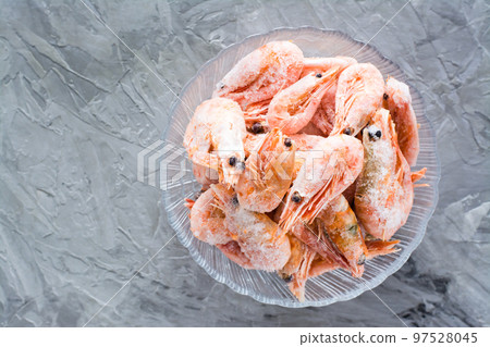 Group of frozen shrimp in a glass bowl on a gray table. Top view 97528045