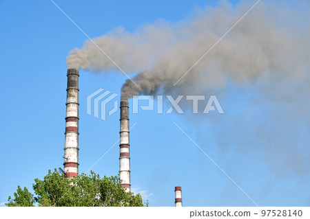 Closeup of thermal power plant high pipes with black smoke moving upwards polluting atmosphere. Production of electrical energy with fossil fuel concept Closeup of thermal power plant high pipes with black smoke moving upwards polluting atmosphere. Production of electrical energy with fossil fuel concept 97528140