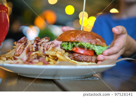 Closeup of tasty burger and french fries with meat on plate in restaurant. 97528141