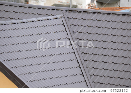Closeup of house roof top covered with metallic shingles.Tiled covering of building 97528152