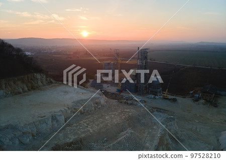 Cement factory at open pit mining of construction sand stone materials. Digging of gravel resources at quarry at sunset Cement factory at open pit mining of construction sand stone materials. Digging of gravel resources at quarry at sunset 97528210