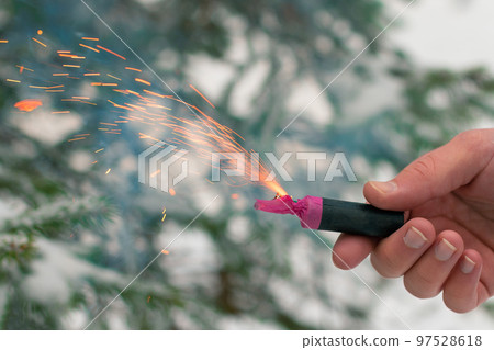 Burning Firecracker in a Hand. Sparks and Smoke of Petard 97528618