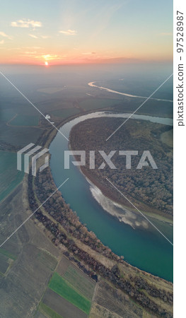 Aerial view of wide river flowing quietly in rural countryside in autumn evening Aerial view of wide river flowing quietly in rural countryside in autumn evening 97528987