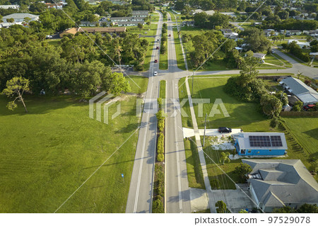 Aerial view of street traffic with driving cars in small town America suburban landscape with private homes between green palm trees in Florida quiet residential area Aerial view of street traffic with driving cars in small town America suburban landscape with private homes between green palm trees in Florida quiet residential area 97529078