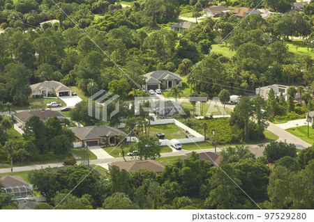 Aerial view of small town America suburban landscape with private homes between green palm trees in Florida quiet residential area Aerial view of small town America suburban landscape with private homes between green palm trees in Florida quiet residential area 97529280