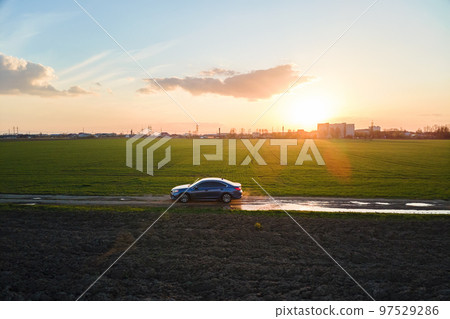 Aerial view of sedan car driving fast on dirt road at sunset. Traveling by vehicle concept. 97529286