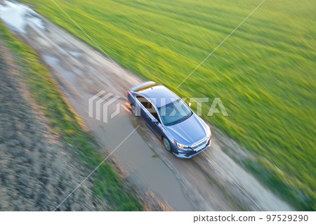 Aerial view of sedan car driving fast on dirt road at sunset. Traveling by vehicle concept. Aerial view of sedan car driving fast on dirt road at sunset. Traveling by vehicle concept. 97529290