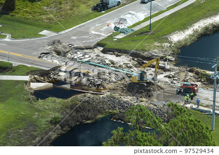 Aerial view of reconstruction of damaged road bridge destroyed by river after flood water washed away asphalt. Rebuilding of ruined transportation infrastructure 97529434