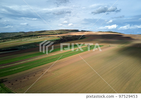 Aerial view of plowed agricultural fields with cultivated fertile soil prepared for planting crops between green woods in spring 97529453