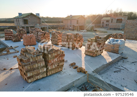 Aerial view of new homes with brick framework walls under construction in rural suburban area. Development of real estate in modern city suburbs Aerial view of new homes with brick framework walls under construction in rural suburban area. Development of real estate in modern city suburbs 97529546