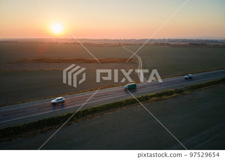 Aerial view of intercity road with fast driving cars at sunset. Top view from drone of highway traffic in evening Aerial view of intercity road with fast driving cars at sunset. Top view from drone of highway traffic in evening 97529654
