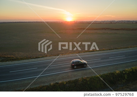 Aerial view of intercity road with blurred fast driving car at sunset. Top view from drone of highway traffic in evening Aerial view of intercity road with blurred fast driving car at sunset. Top view from drone of highway traffic in evening 97529768