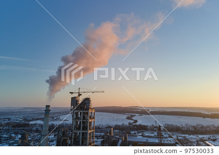 Aerial view of cement factory with high concrete plant structure and tower cranes at industrial production area. Greenhouse gas smoke polluting atmosphere. Manufacture and global industry concept. 97530033