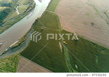 Aerial landscape view of village houses and distant green cultivated agricultural fields with growing crops on bright summer day 97530293