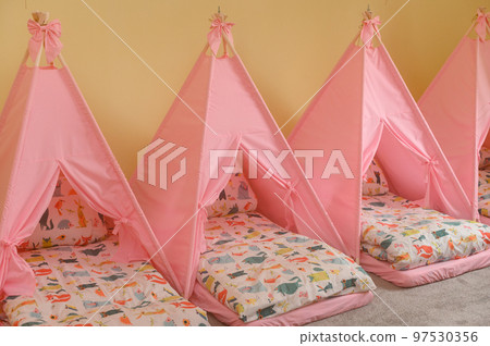 Baby cots in the kindergarten for naps in the form of tents. 97530356