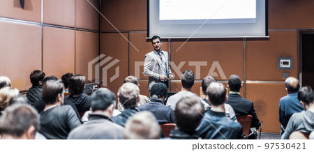 Speaker giving a talk in conference hall at business meeting event. Rear view of unrecognizable people in audience at the conference hall. Business and entrepreneurship concept. Speaker giving a talk in conference hall at business meeting event. Rear view of unrecognizable people in audience at the conference hall. Business and entrepreneurship concept. 97530421