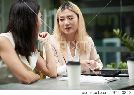 Serious businesswoman listening to colleague explaining idea at meeting 97530800