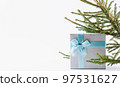 Christmas background. A box with a gift tied with a ribbon and a spruce branch. 97531627