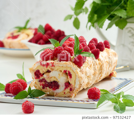 Baked meringue roll with cream and fresh red raspberry, white background. Baked meringue roll with cream and fresh red raspberry, white background. 97532427