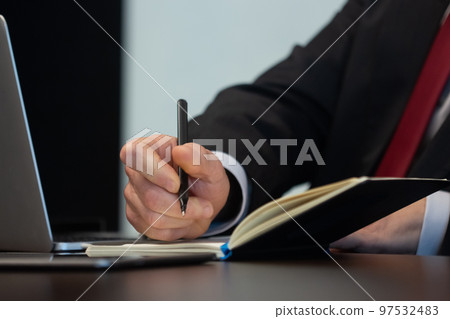 Close-up of male hands writing down data with pen Close-up of male hands writing down data with pen 97532483