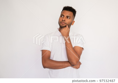 Portrait of pensive young man standing with hand on chin Portrait of pensive young man standing with hand on chin 97532487