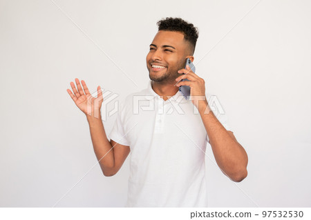 Cheerful young man talking on mobile phone waving his hand 97532530