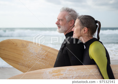 Side view of happy aged couple surfing together Side view of happy aged couple surfing together 97532541