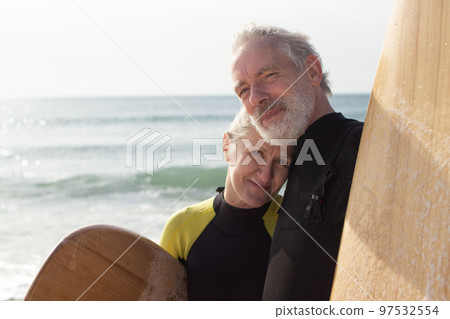 Portrait of happy senior couple with surfboards near sea 97532554