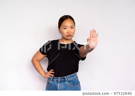 Portrait of serious young woman making stop gesture 97532640