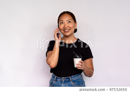 Portrait of happy young woman with coffee talking on smartphone Portrait of happy young woman with coffee talking on smartphone 97532650