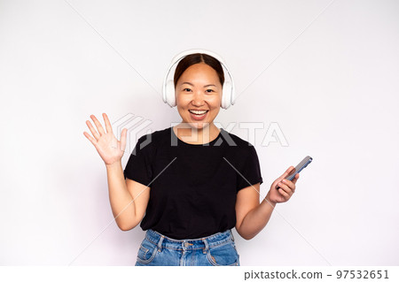 Portrait of excited young woman in headphones holding smartphone Portrait of excited young woman in headphones holding smartphone 97532651