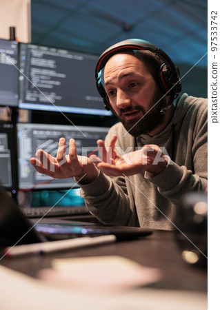 Software developer talking on online videoconference with laptop and webcam, using remote videocall to have internet conversation. Attending teleconference call to chat on headphones. Software developer talking on online videoconference with laptop and webcam, using remote videocall to have internet conversation. Attending teleconference call to chat on headphones. 97533742