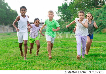 Five smiling kids running and laughing in park Five smiling kids running and laughing in park 97535310