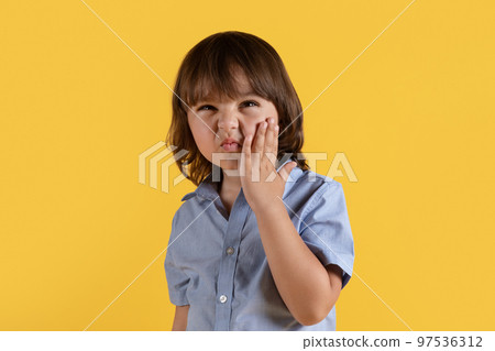 Kids dental care. Cute little boy suffering from acute tooth pain, touching painful cheek and frowning face, free space Kids dental care. Cute little boy suffering from acute tooth pain, touching painful cheek and frowning face, free space 97536312