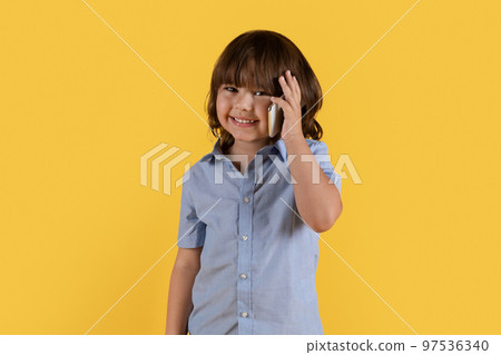 Mobile connection anywhere. Adorable little boy talking on cellphone with far living family or friend, smiling to camera Mobile connection anywhere. Adorable little boy talking on cellphone with far living family or friend, smiling to camera 97536340