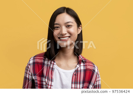 Happy person. Portrait of young asian lady with beautiful smile, looking at camera, posing in studio, yellow background Happy person. Portrait of young asian lady with beautiful smile, looking at camera, posing in studio, yellow background 97536424