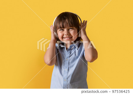 Little music lover. Studio portrait of happy little boy in wireless headphones, enjoying great sound of dynamic track Little music lover. Studio portrait of happy little boy in wireless headphones, enjoying great sound of dynamic track 97536425