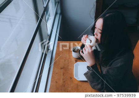 Photo of young woman eating donuts at home 97539939