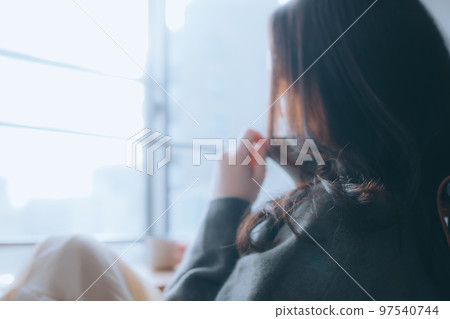 Photo of a young woman eating breakfast in her room 97540744