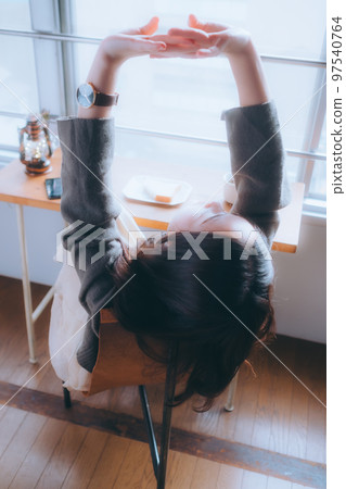 Photo of a young woman eating breakfast in her room 97540764