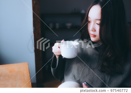 Photo of a young woman eating breakfast in her room 97540772