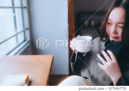 一位年輕女子在她的房間裡吃早餐的照片 一位年輕女子在她的房間裡吃早餐的照片 97540778