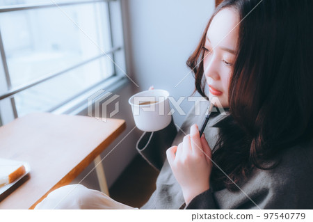 Photo of a young woman eating breakfast in her room Photo of a young woman eating breakfast in her room 97540779
