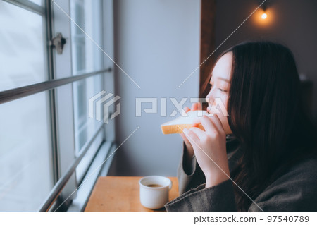 Photo of a young woman eating breakfast in her room 97540789