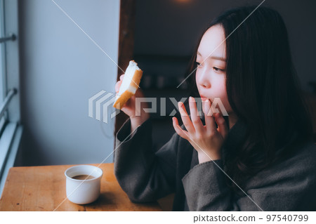 Photo of a young woman eating breakfast in her room Photo of a young woman eating breakfast in her room 97540799